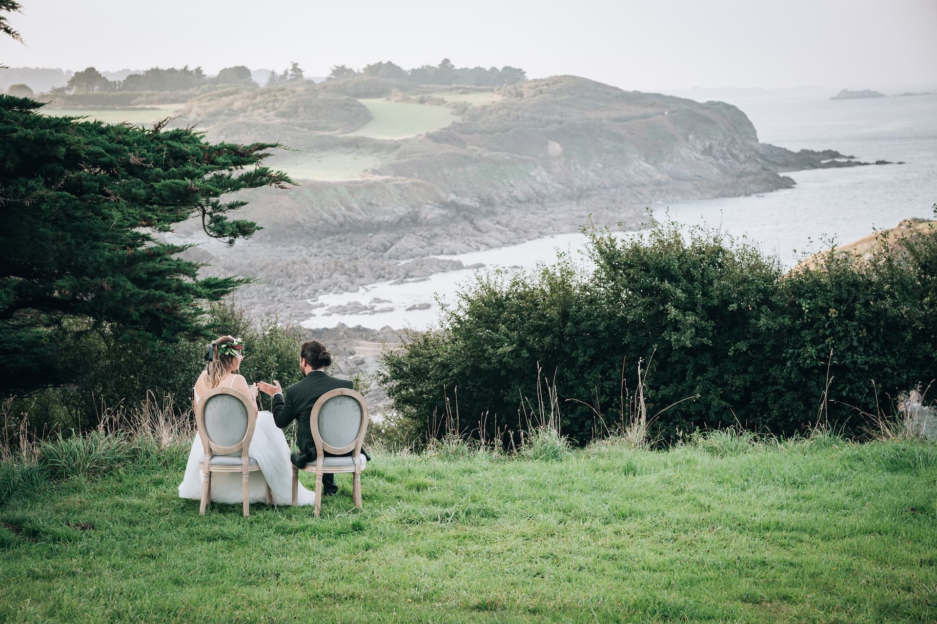 Mariés assis sur des chaises face à la mer