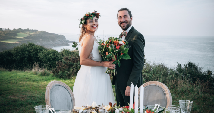 Deux jeunes mariés souriants devant leur table de mariage et la mer en arrière plan