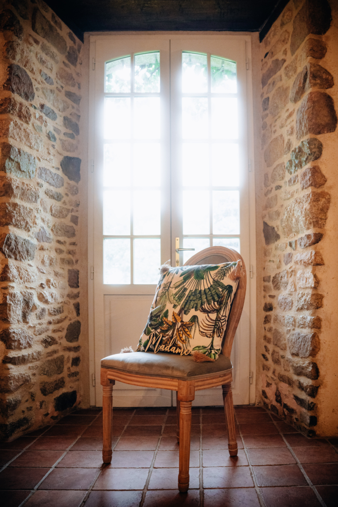 Chaise médaillon en velour vert pâle et bois brut devant une fenêtre en contre jour