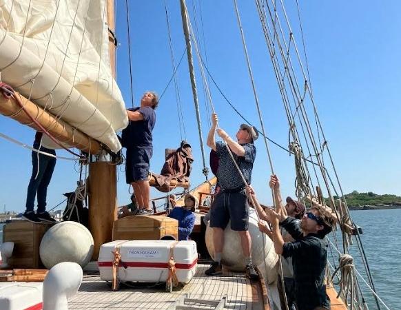 équipe à bord d'un voilier en train de hisser une voile - séminaire glad events en Bretagne-
