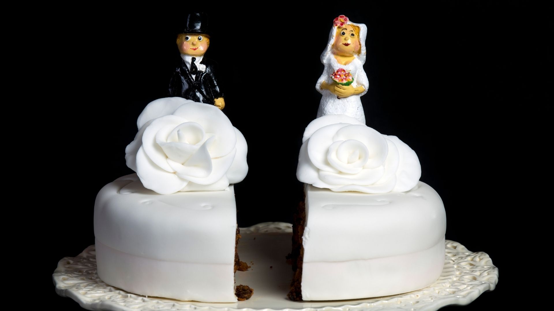 gâteau de mariage blanc coupé en deux séparant les deux époux chacun sur un part