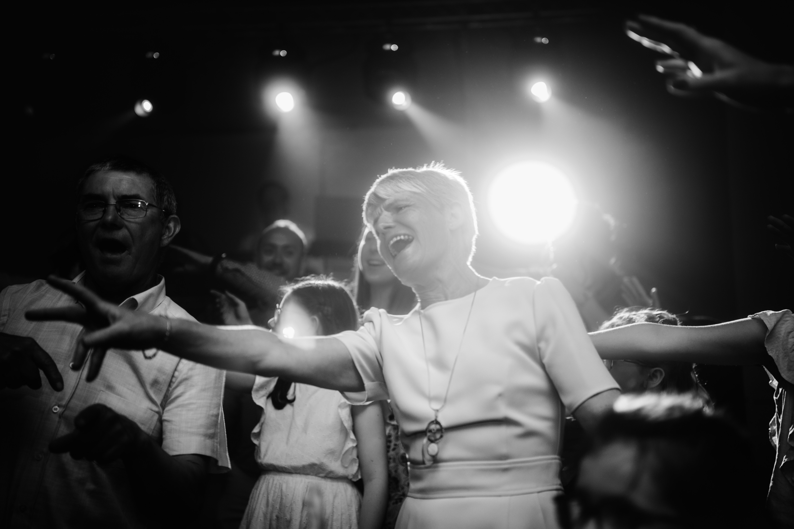 Photo noir et blanc sur laquelle on voit une femme qui chante, le bras tendu, éclairé par des projecteurs lors d'une fête by Glad events