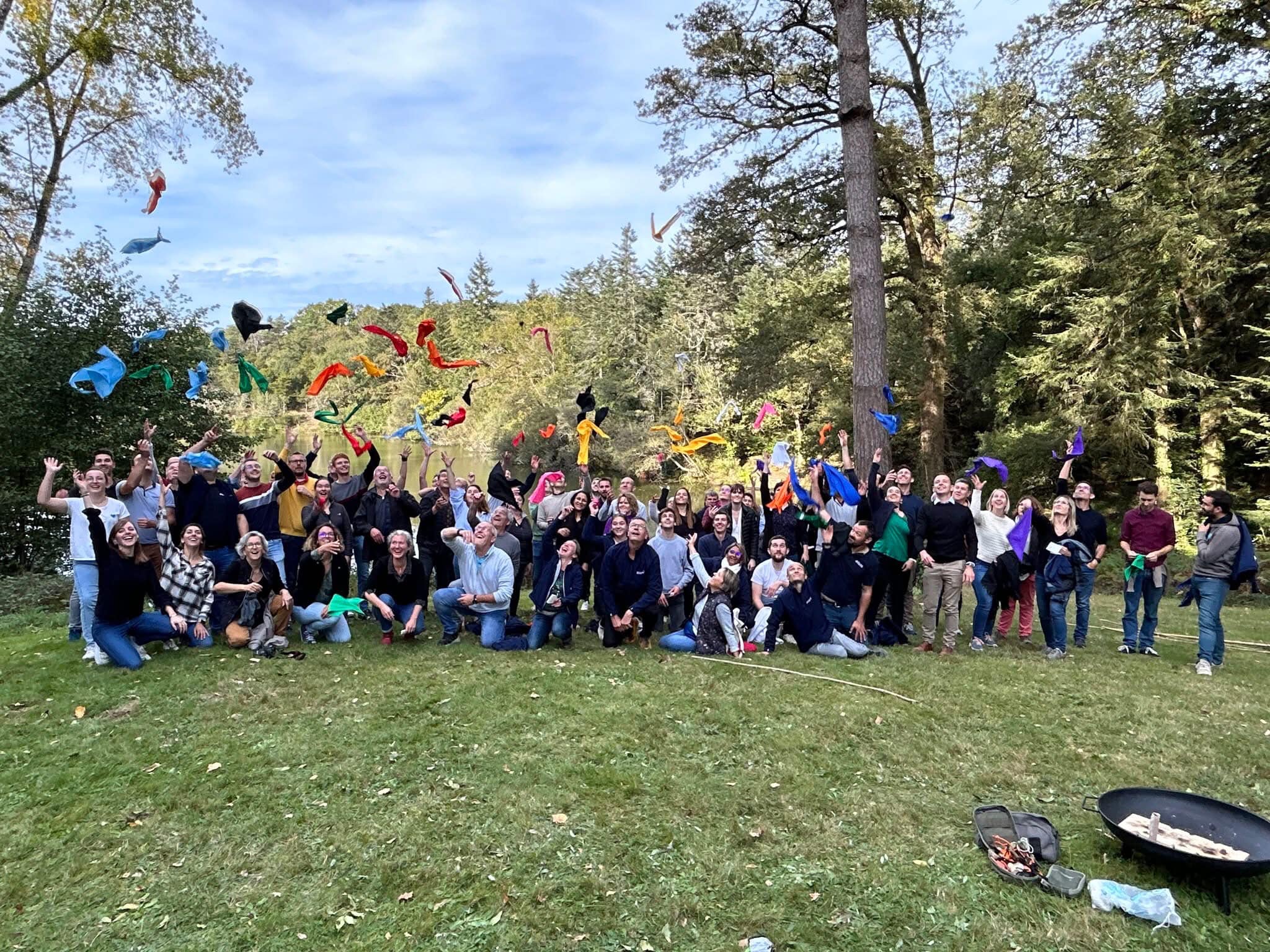 Tous ensemble par Glad events team building Groupe rassemblé sous les arbres lors d'un team building Glad events en Bretagne. Certains lancent leur fanions de couleurs différentes qui symbolisaient l'équipe à laquelle ils appartenait durant le jeu. Tous sourient et sur heureux