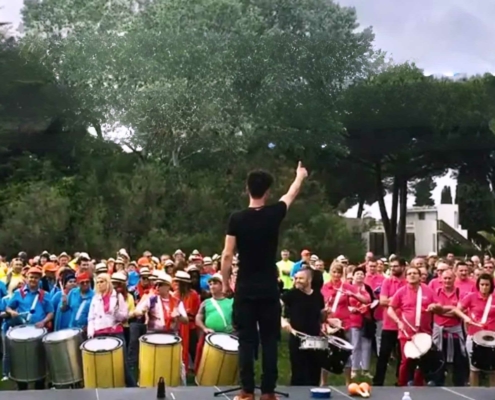 Les tambours du Cap - foule devant un chef d'orchestre , de dos, sur une scène, jouant en rythme d'instruments à percussion brésiliens