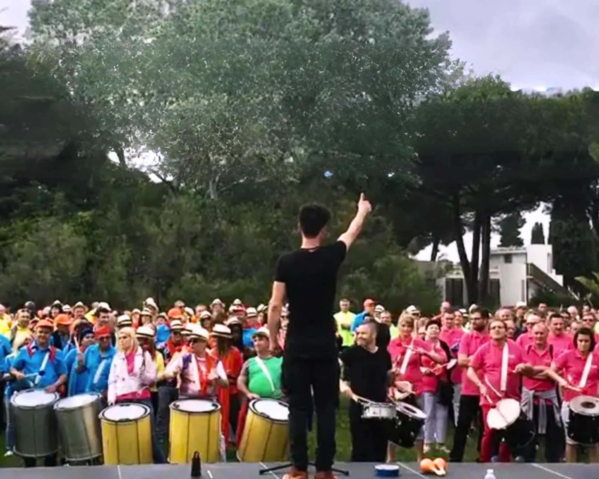 Tambours du cap 3 team building Glad events pro Les tambours du Cap - foule devant un chef d'orchestre , de dos, sur une scène, jouant en rythme d'instruments à percussion brésiliens