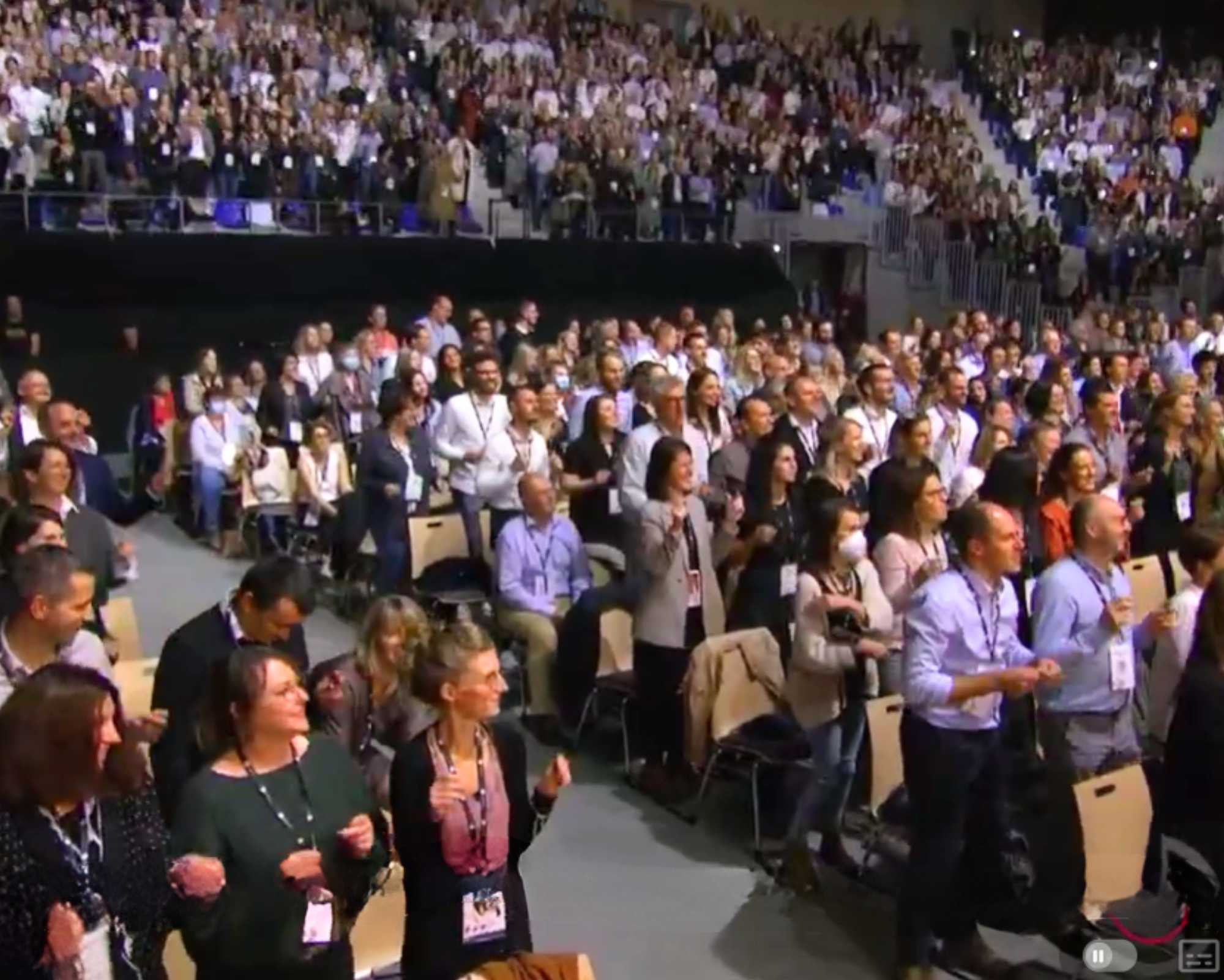 centainements de personnes regroupées dans une salle de spectacle, debout en cours de percussion corporel pour un réveil vitaminé avant la prochaine conférence par Glad events