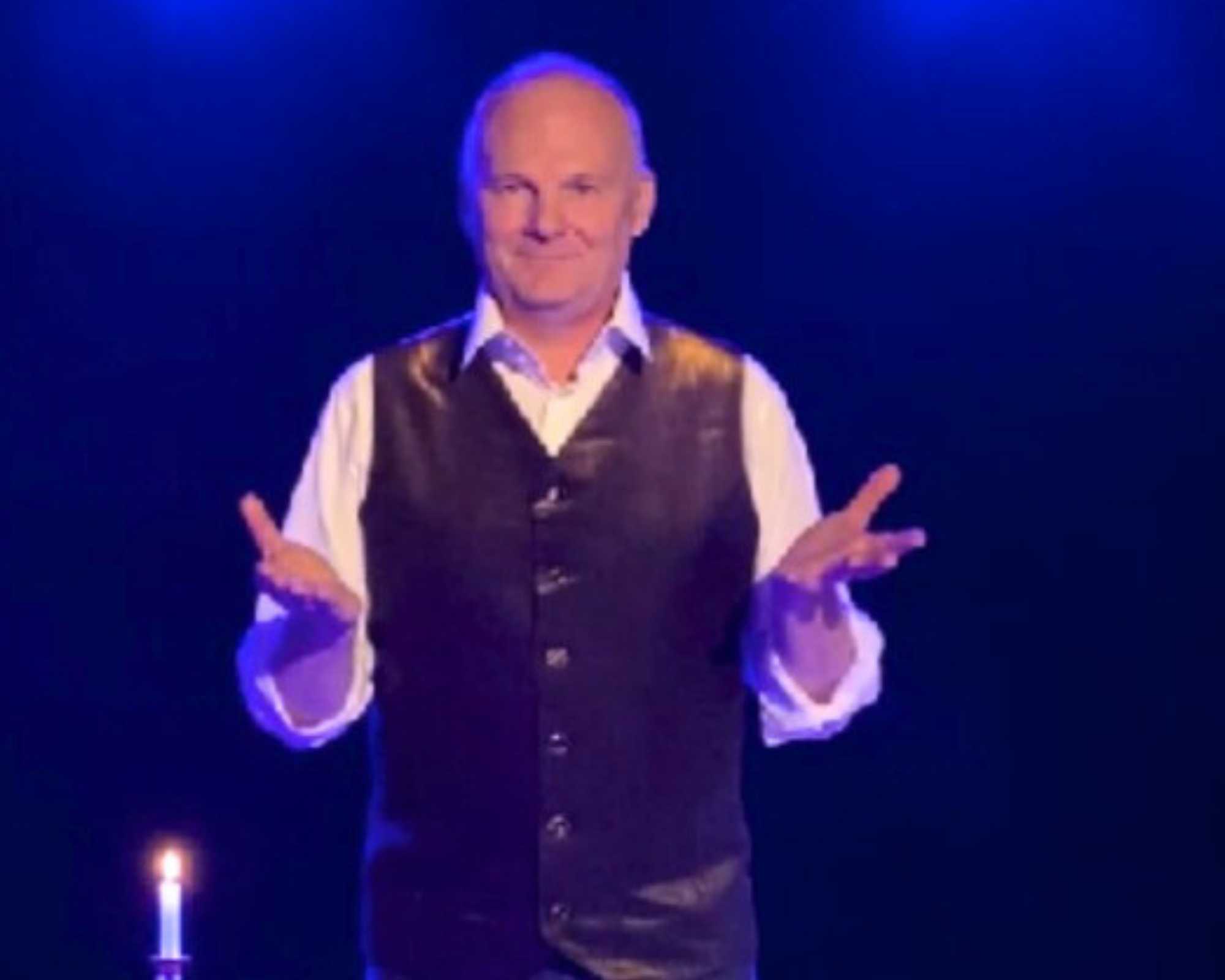 Magicien du goût de Glad events montrant ses mains sur scène, laors qu'il est en train de faire un tour de magie lors de son spectacle la symphonie du goût