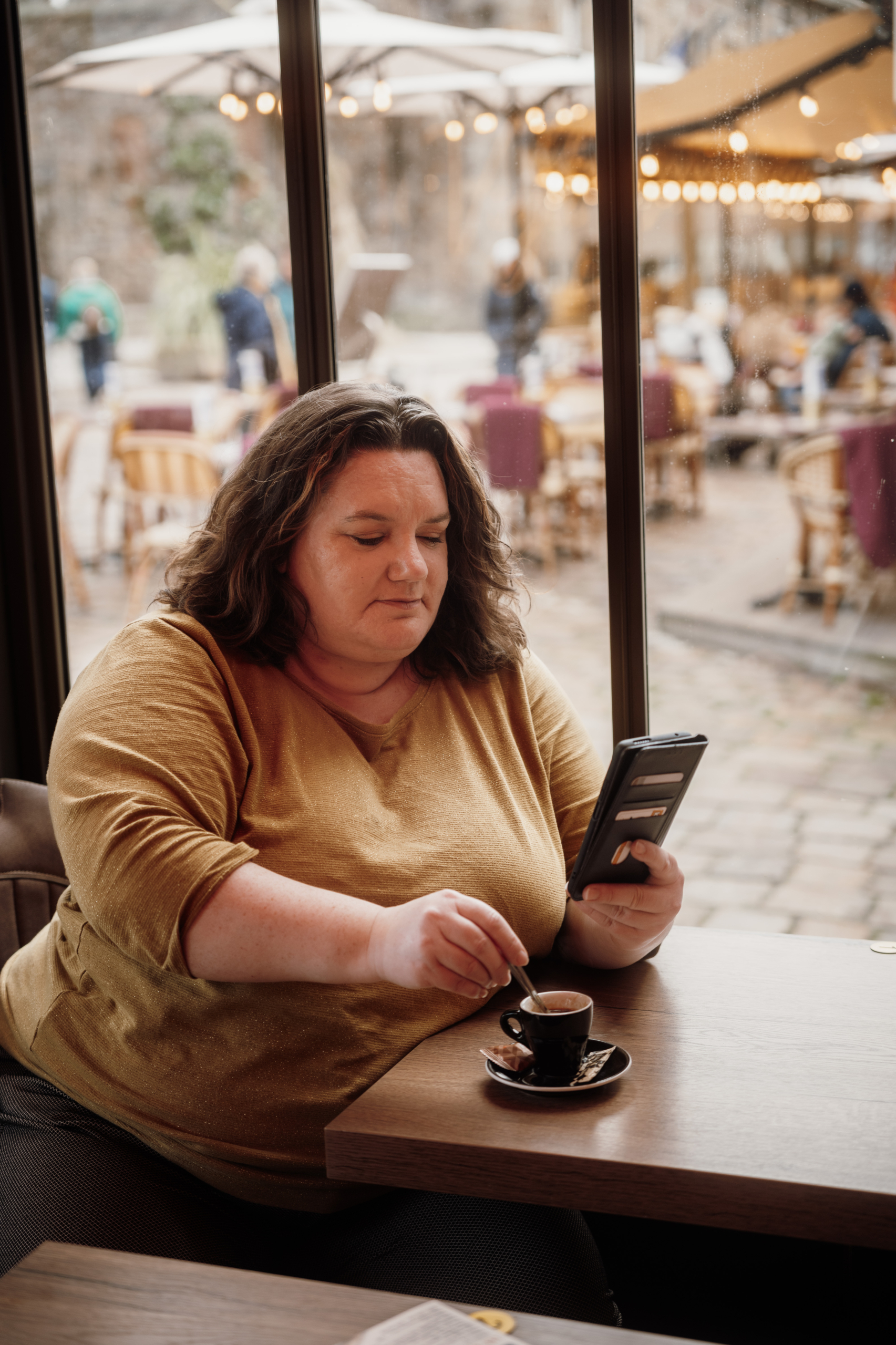 Gwladys Cren - Directrice de l'agence évènementielle Glad events Gwladys Cren, Directrice de Glad events à table dans la jolie véranda d'un café de centre vielle à St Malo. Elle tourne sa cuillère dans la tasse pendant qu'elle lit sur son téléphone portable
